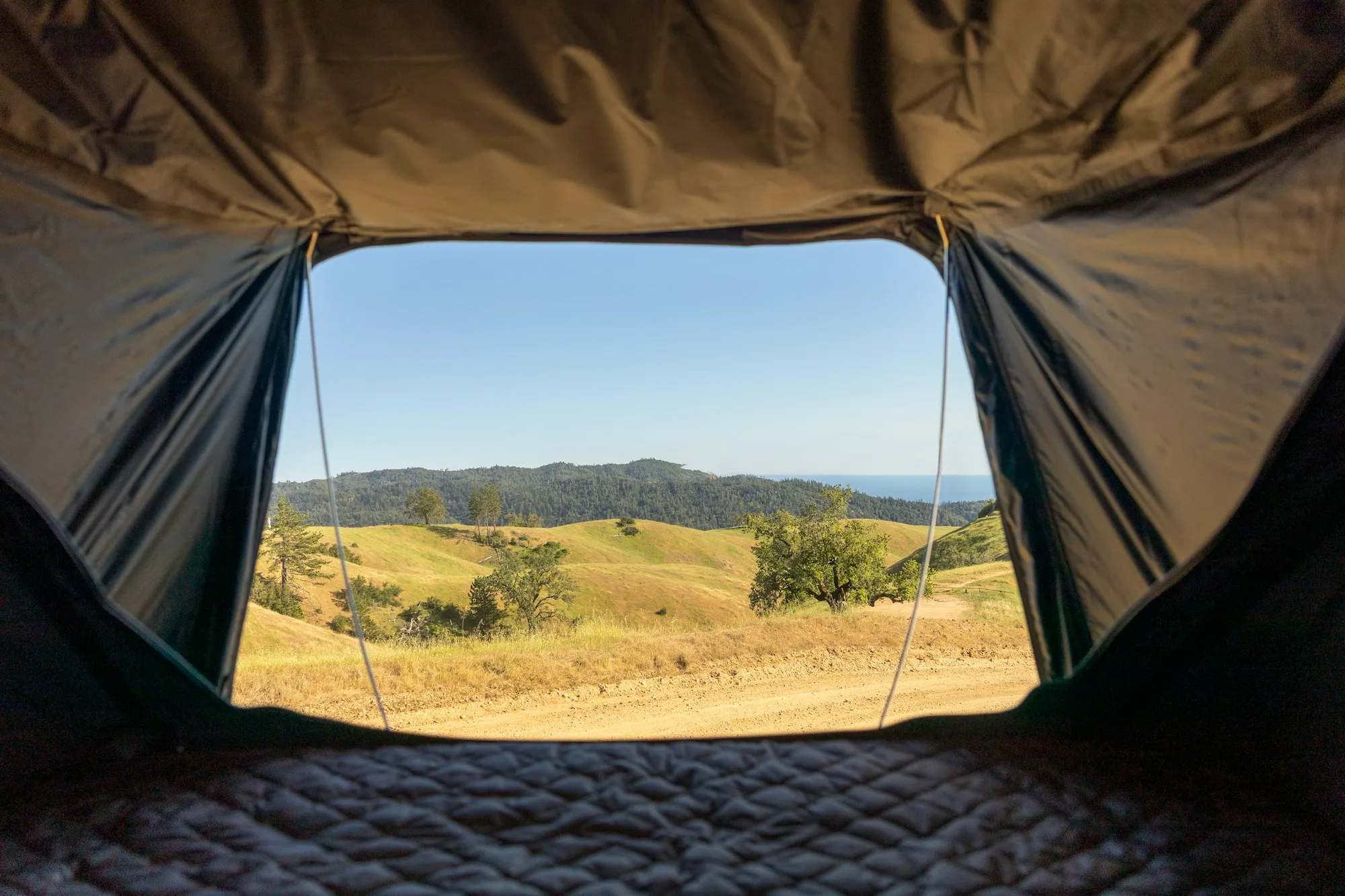 Blick aus einem Zelt auf eine Hügellandschaft